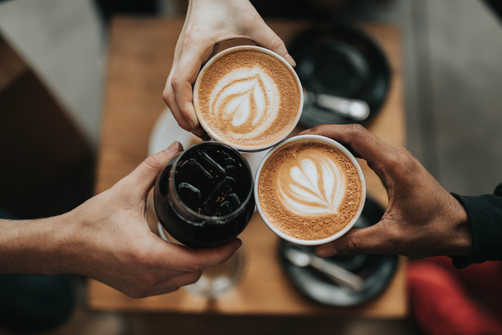 kaffeetrinken-im-babycafe drei Kaffeevarietäten werden zusammengehalten, darunter befindet sich ein Tisch mit den Untertassen und Löffeln
