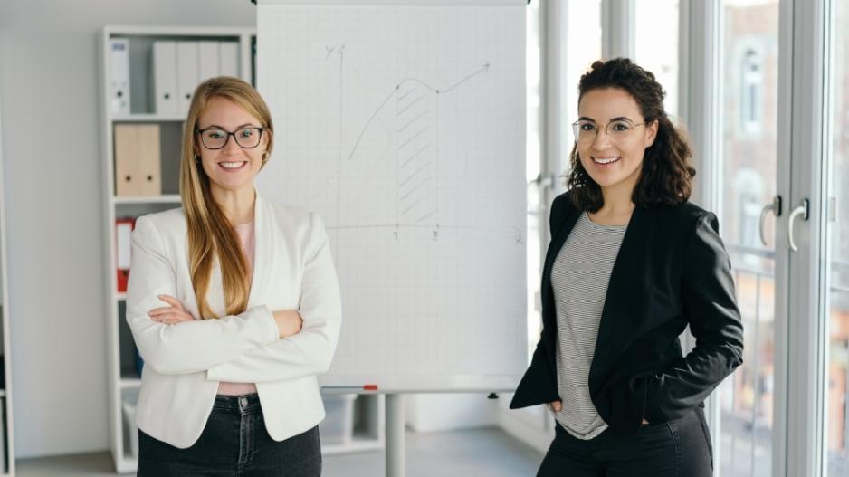 zwei Frauen stehen lächelnd im Office