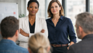 2 Frauen vor einer Gruppe Menschen, die von hinten zu sehen ist